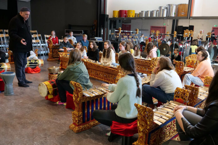 Un professeur fait découvrir des instruments traditionnels étrangers à un groupe de jeunes lors d'un cours de musique.