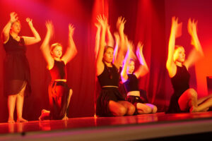 Plusieurs jeunes filles dansant de façon synchronisées sur scène.