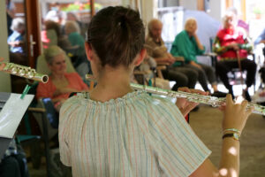 Jeune fille jouant de la flute traversière lors d'un concert organisé au sein de l'EHPAD.