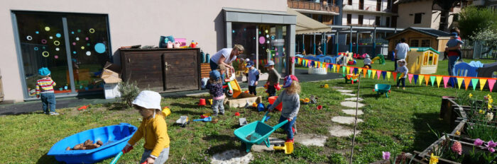Plusieurs enfants qui jouent dans un grand jardin avec plein de jouet.