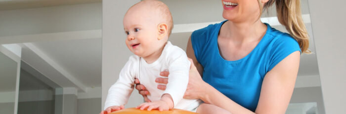 Assistante maternelle aide un bébé à développer sa motricité.
