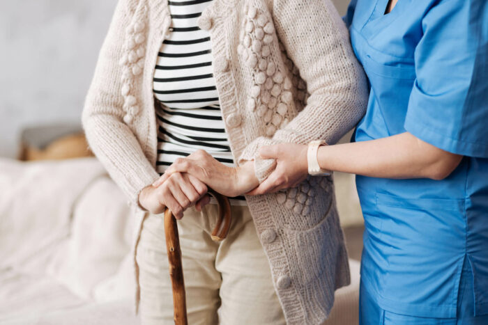 Une infirmière aide une personne âgée à se redresser.